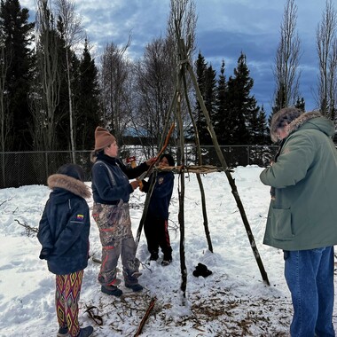 student gathered around the smokehouse